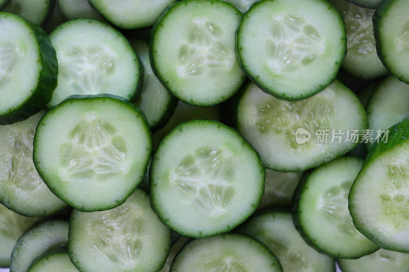 多层黄瓜(Cucumis sativus)切片的全画幅图像，堆叠显示绿色的皮肤和白色的果肉与白色的种子，健康饮食海报壁纸背景设计，高架视图